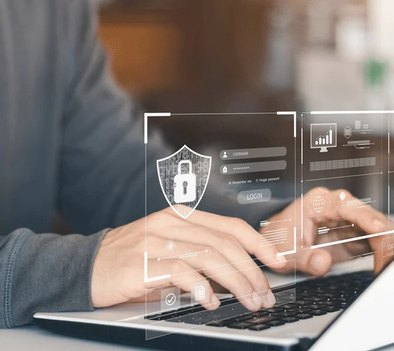 Persoon werkt op laptop met beeldscherm dat slotpictogram, inlogvelden en statistiekdiagrammen toont