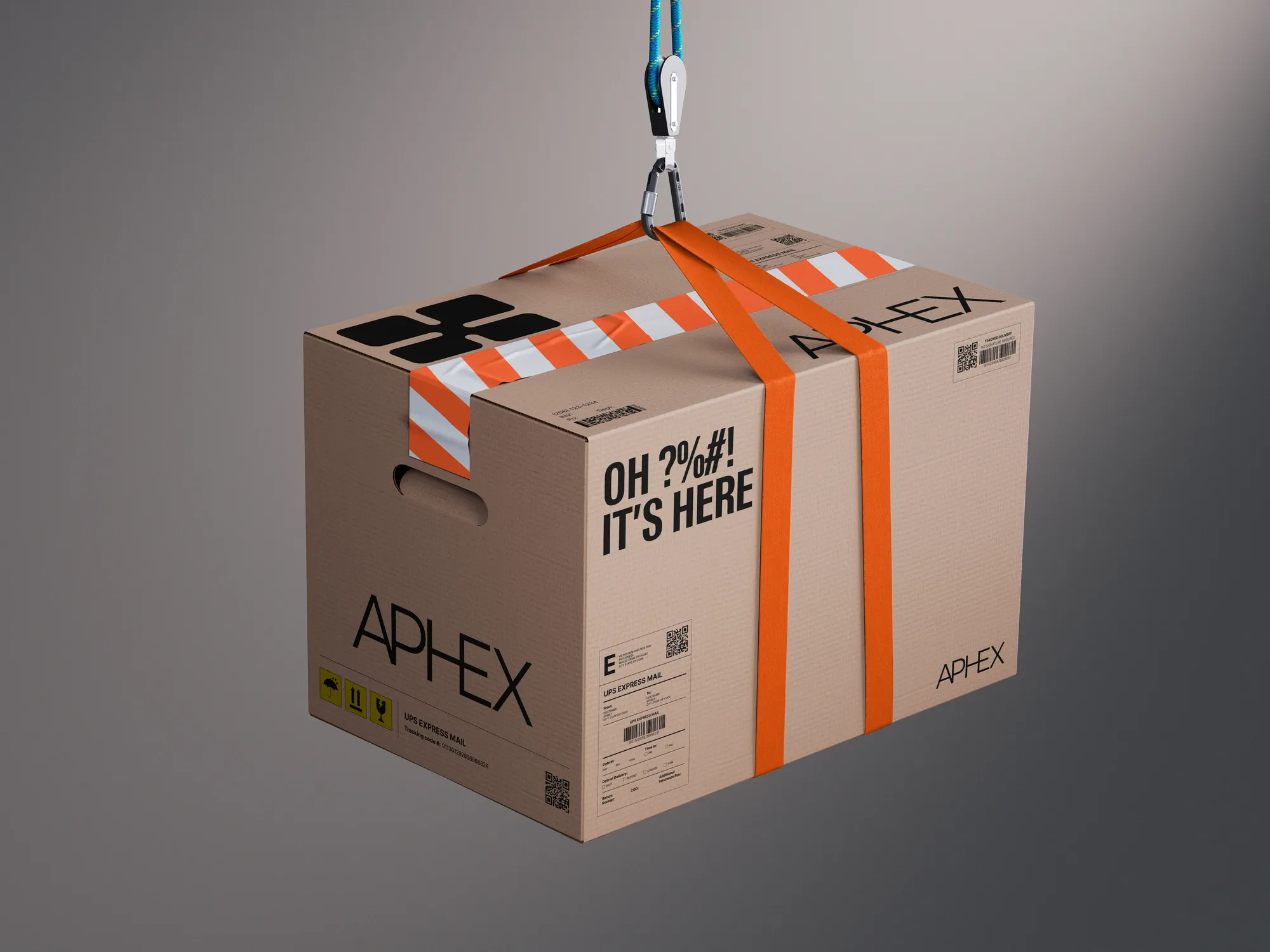 Kartonnen doos met tekst 'APHEX' en 'OH! ?%#!! IT'S HERE', hangend aan haak tegen grijze achtergrond