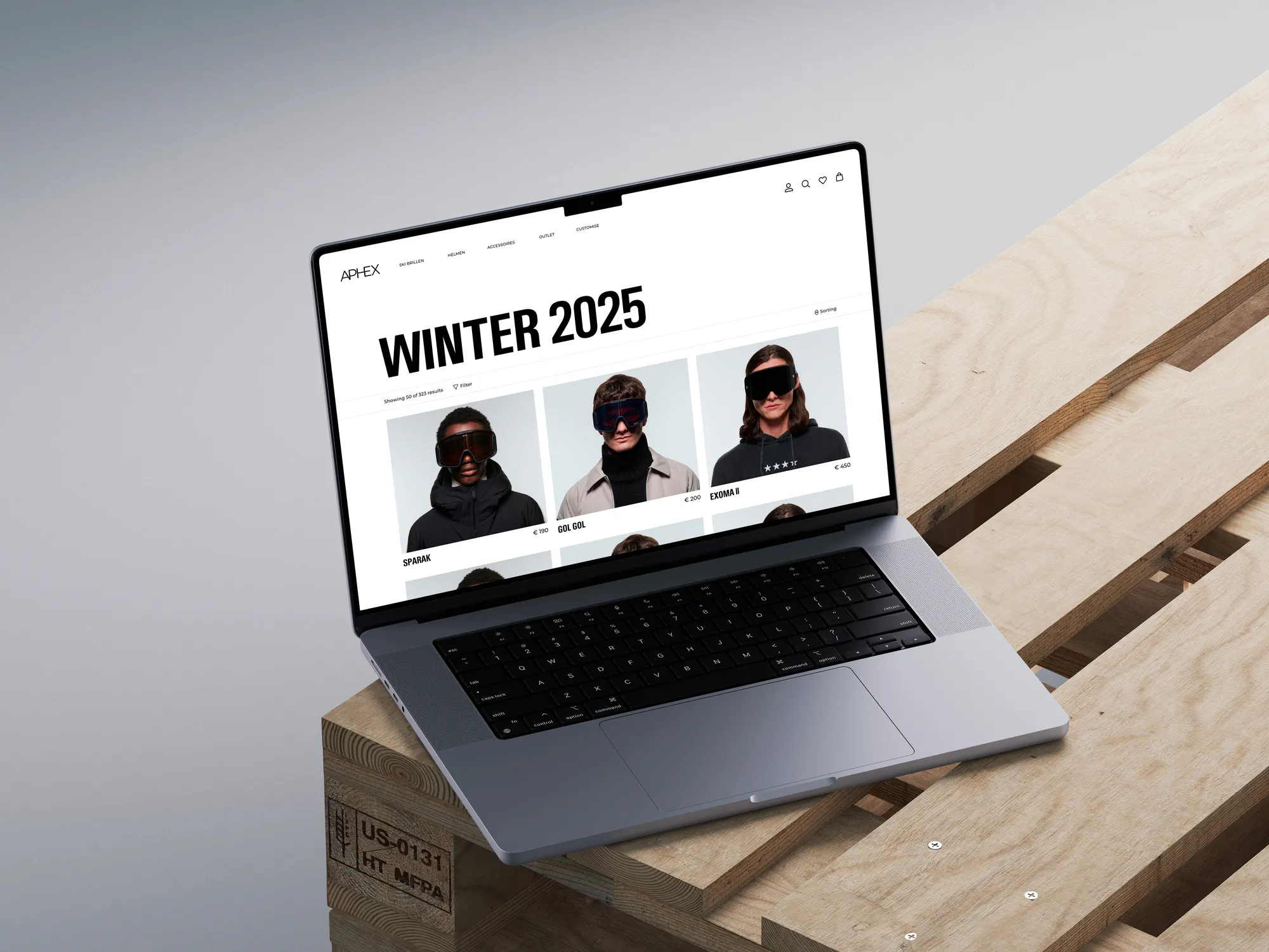 Laptop op houten pallet met website over winter 2025 en modellen met skibrillen en prijzen